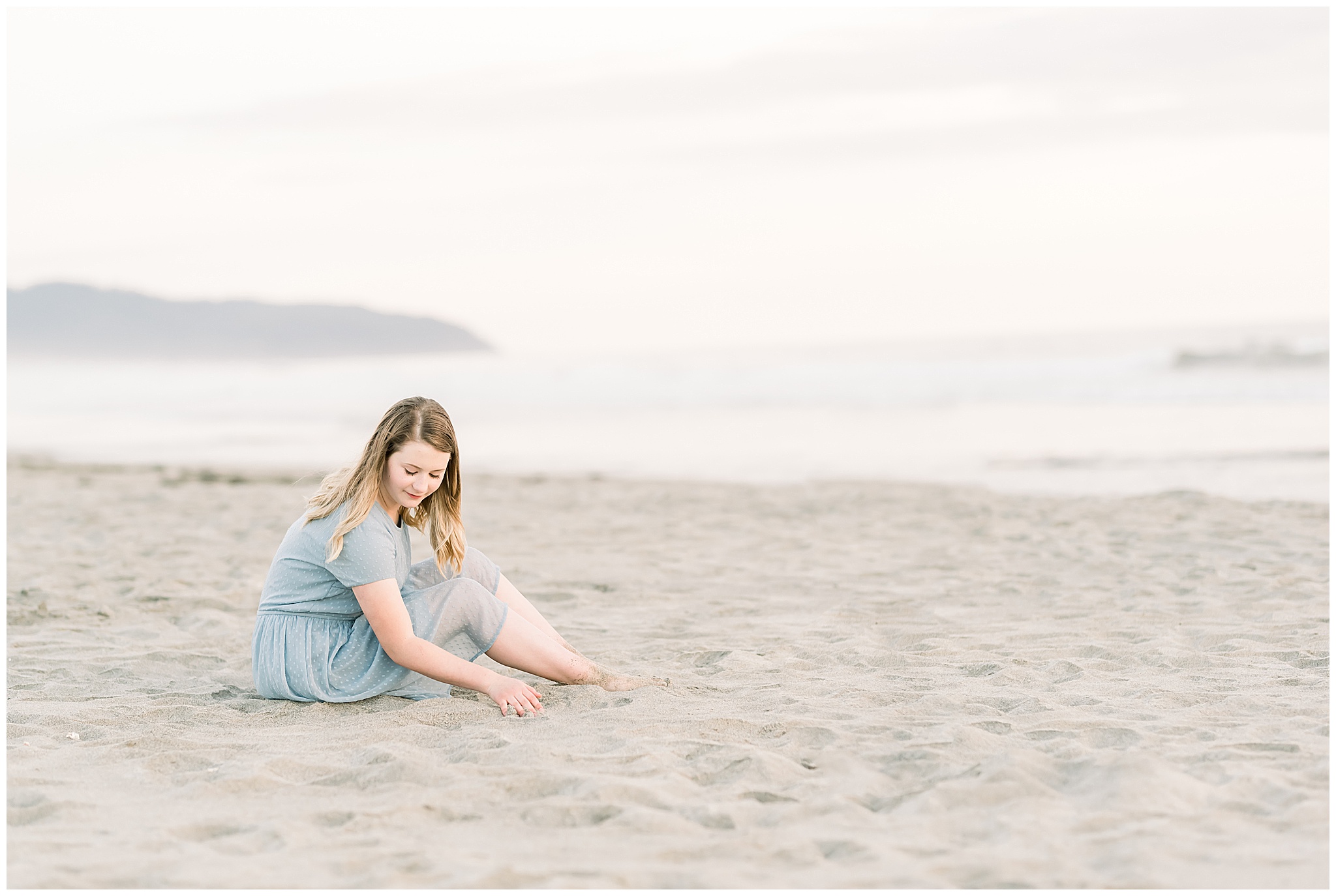 Teenage girl sitting in the sand on the Oregon coast